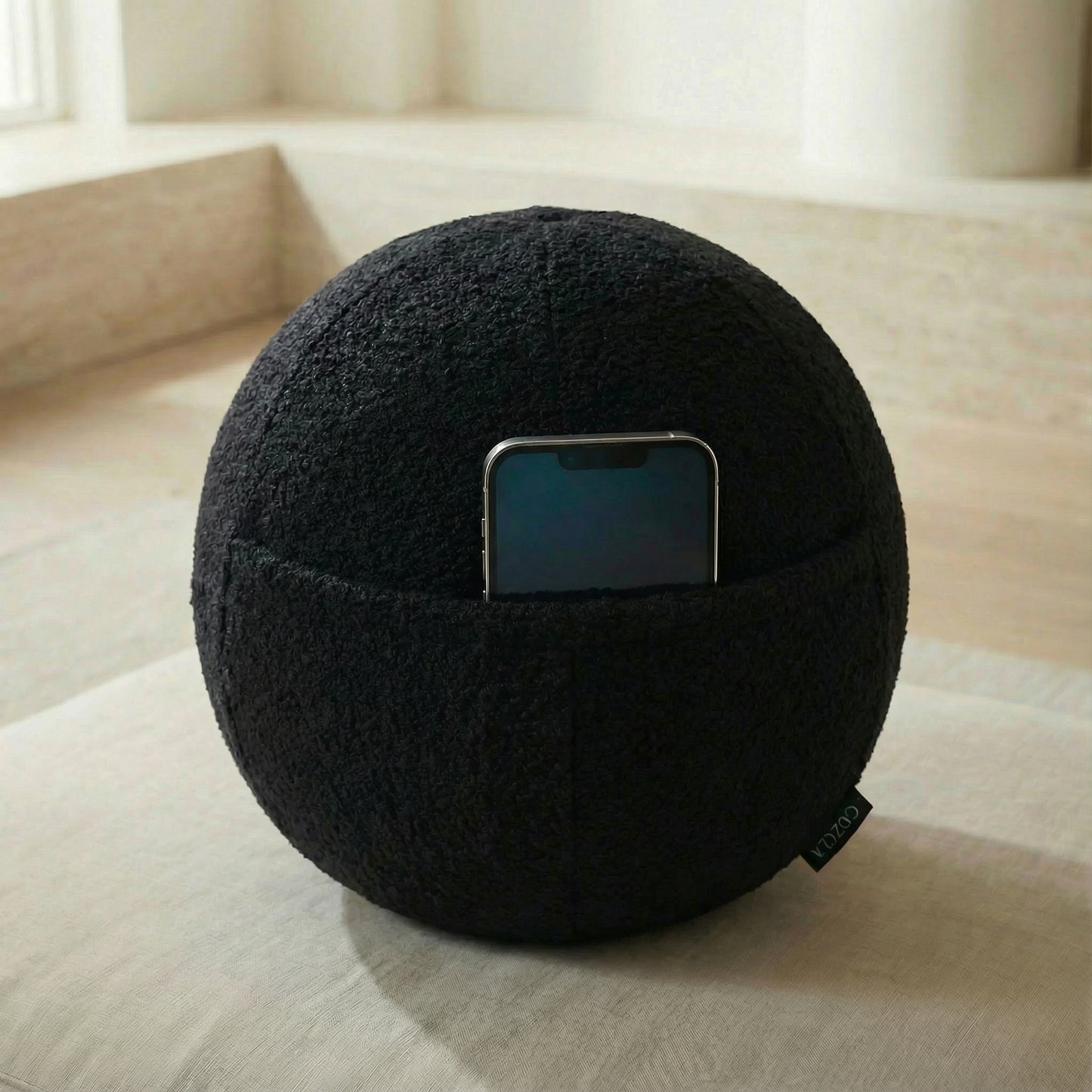 Phone stored in the hidden pocket of the Orb Black Bouclé pillow