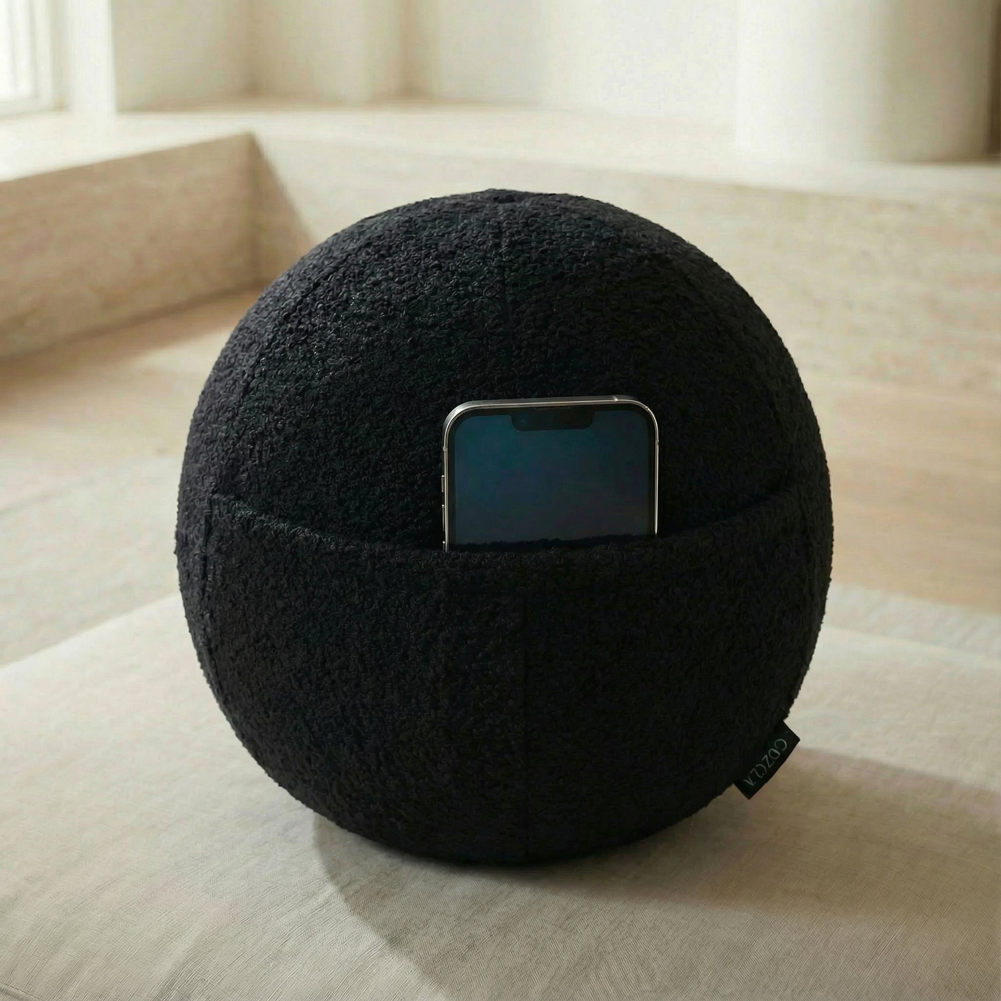 Phone stored in the hidden pocket of the Orb Black Bouclé pillow