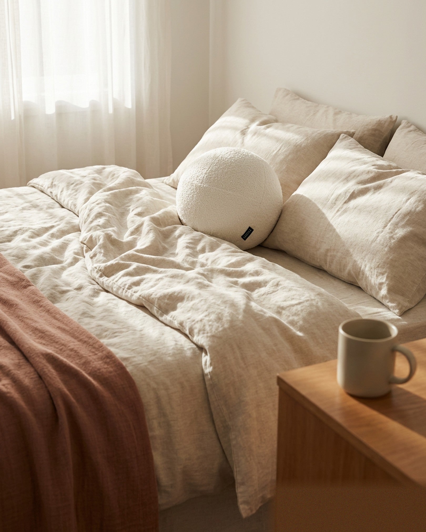 Orb white bouclé sphere pillow styled on bed in modern bedroom setting